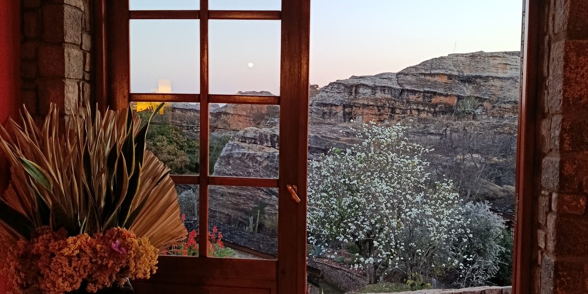 Porte voûtée ouverte sur un paysage de plateaux rocheux, au crépuscule